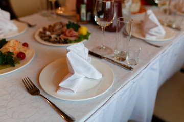 Plate with fork, knife and napkin served on the wedding table, all ready for the holiday.