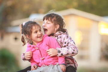 Obraz premium outdoor portrait of two young happy children, girls - sisters - playing in park on natural background