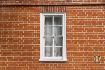 Fototapeta na wymiar White vintage wooden window on a restored red brick wall