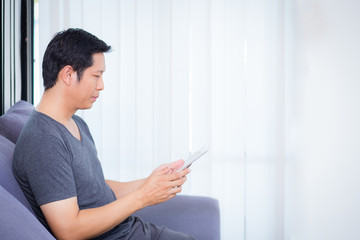 businessman watching media content in a tablet sitting on a sofa at home.