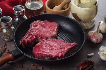 Raw fresh meat rib eye steak composition in grill pan on wooden background