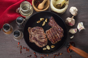 Grilled rib eye steak composition on grill iron pan on wooden background