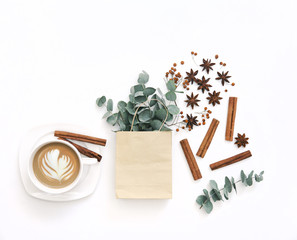 Workspace with cup of coffee and eucalyptus branches. Flat lay, top view