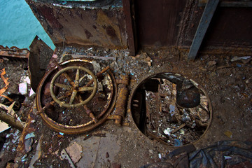 Fototapeta na wymiar Rusty hatch with the steering wheel Inside rotten abandoned Russian warship