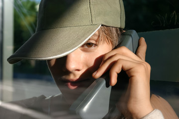 Veraltete Technik: Jugendlicher mit Telefonhörer spricht in der Telefonzelle