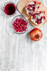 Red sliced pomegranate and juice in glass on wooden background top view mock up