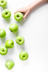 Fototapeta na wymiar natural food design with green apples in hands white desk background top view