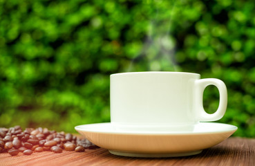 Good morning with white hot drink cup and smoke, coffee beans on blur green background. Start up concept in the garden.