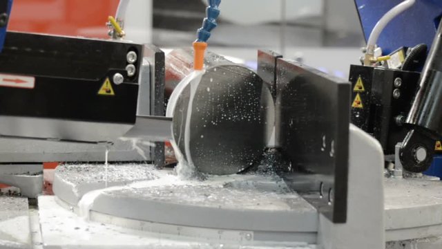 A horizontal band saw machine saws a thick metal circle.