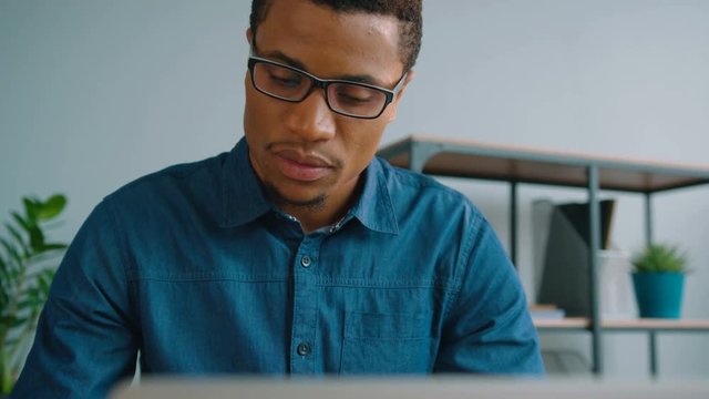 Concentrated african american business man working with laptop computer at the office. Man typing on the laptop keyboard. Close up