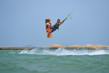 Professional kite boarding rider sportsman jumps high acrobatics kiteboarding trick with raley from water. Recreational activity and extreme active water sports, hobby and fun time
