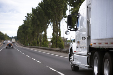 Modern semi truck on wide highway stretching into distance