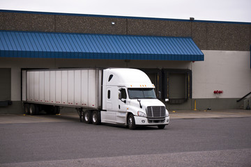 White truck with a trailer in a warehouse on the unloading