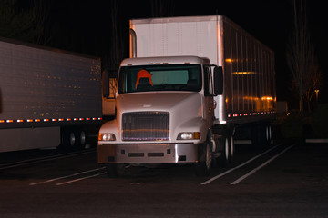 White semi truck trailer light reflection on parking lot in night