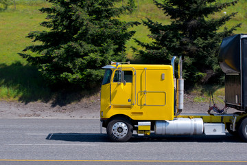 Fototapeta na wymiar Yellow cabover big rig semi truck old model on road