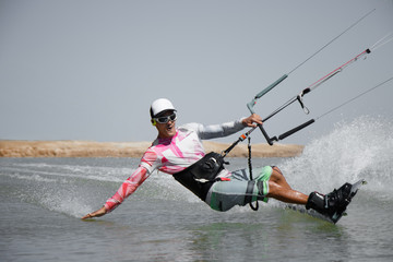 Fototapeta na wymiar Kite surfer rides ideal flat water of the lake lagoon with kite flying in sky. Recreation activity and active extreme water sports kiteboarding, hobby and fun in vacation time.
