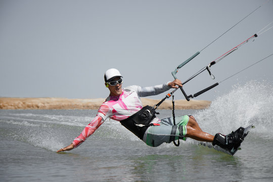Kite surfer rides ideal flat water of the lake lagoon with kite flying in sky. Recreation activity and active extreme water sports kiteboarding, hobby and fun in vacation time.