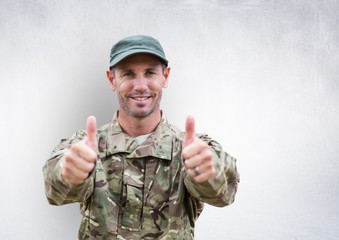 soldier thumbs up and smiling. concrete wall