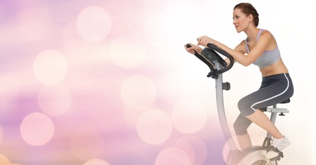 Young woman doing exercise bike with pink background