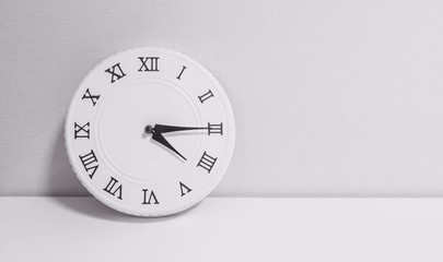 Closeup white clock for decorate show a quarter past four o'clock or 4:15 p.m. on white wood desk and wallpaper textured background in black and white tone with copy space