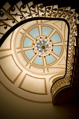 Stairs rails and chandelier on ceiling with geometric art