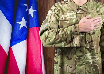 Fototapeta premium soldier with the hand on the hearth and the usa flag behind