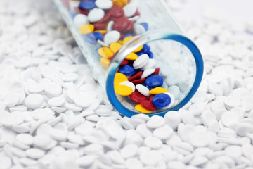close up of colorful plastic polymer granules in test tube on white