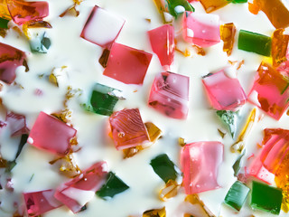 Pieces of colored opaque sweets jelly in milk cream