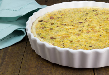Quiche with cheese, bacon and mushroom on rustic wooden table - Open pie in white dish with selective focus