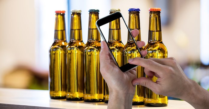 Hand taking picture of beer bottles through smart phone