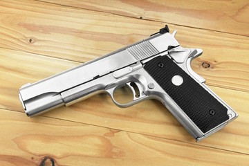 Semi-automatic handgun on grey wooden background, .45 pistol. Guns.