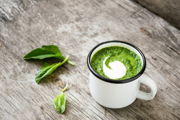 Easy homemade soup with fresh spinach in a white mug on the kitchen table