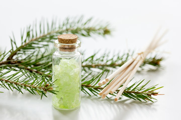 cosmetic spruce salt in bottles with fur branches on white table background