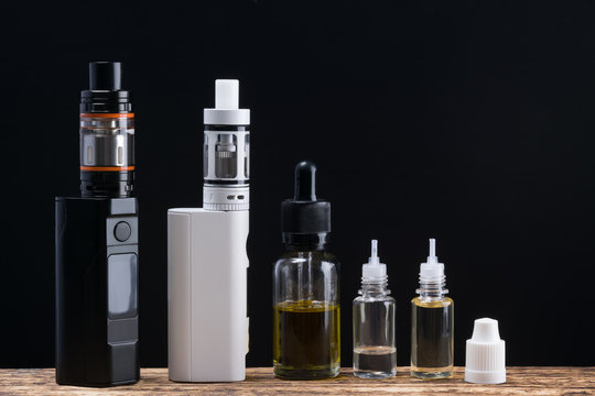 A set of electronic smoking appliances laid out on a table, on a black background