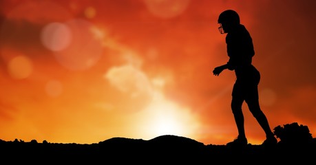 Silhouette rugby player on field against sky during sunset