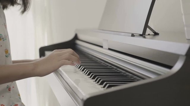 4K : Slow motion of Asian girl playing piano, Pan shot
