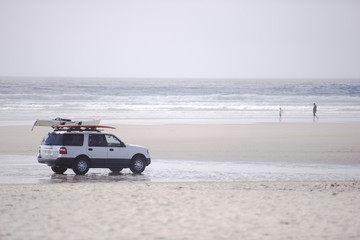 Fototapeta na wymiar Car with surfboards on the Pacific coast beach