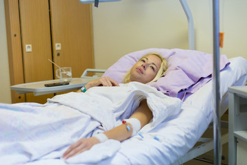 Bedridden female patient lying in hospital bed, recovering after surgery.