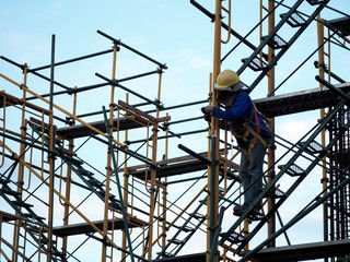 Fototapeta premium Construction workers working on scaffolding, Man Working on the Working at height with blue sky at construction site
