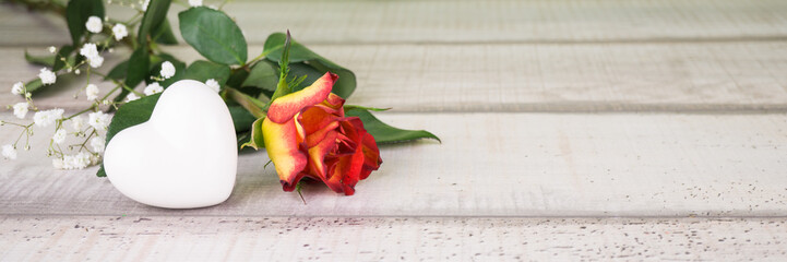 Eine Rose und ein weißes Herz aus Porzellan, Holzhintergrund mit Textfreiraum
