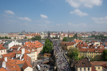PAGUE, CZECH REPUBLIC - MAY 6, 2017: Many tourists are walking through the Charles Bridge and on the bridge, the villagers brought the goods to sell, background old town and zizkov Television Tower.