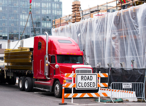 Red Semi Truck Unloading Metal Farms On Construction Side In City