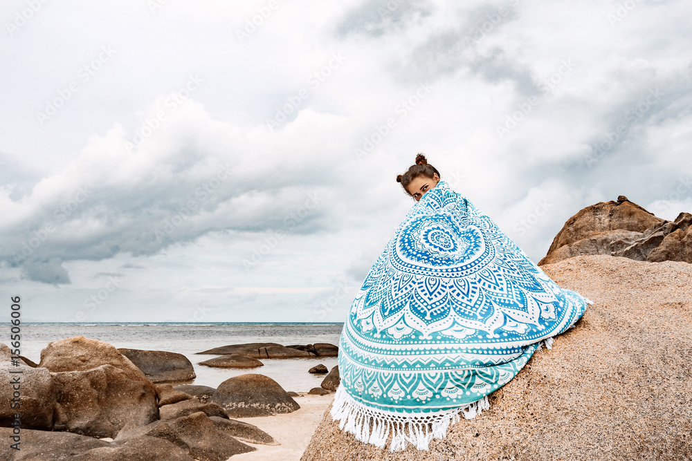 Wall mural beautiful young woman covered with stylish mat on the beach