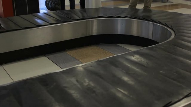 Travelers take their luggage from belt in the airport. Baggage claim area