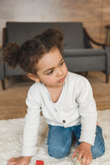 portrait of little pensive girl sitting on floor at home