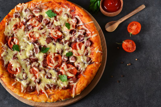 Home pizza with salami, tomato and cheese on a black background