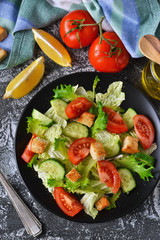 Vegetable salad with cucumber, tomatoes and olive oil on a concrete background