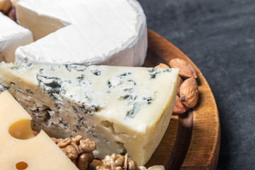 Assorted fresh cheese, fruits and nuts on a wooden table