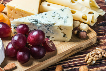 Assorted fresh cheese, fruits and nuts on a wooden table