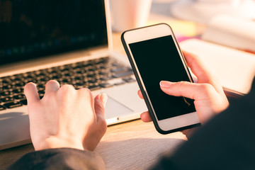 Close-up partial view of businesswoman using laptop and smartphone with blank screens